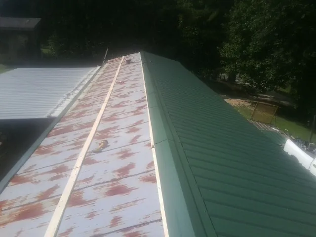 Old rusted panels beside newly installed green metal roofing — Wind Damage Roof Repair by Roofing Brothers in Center Line
