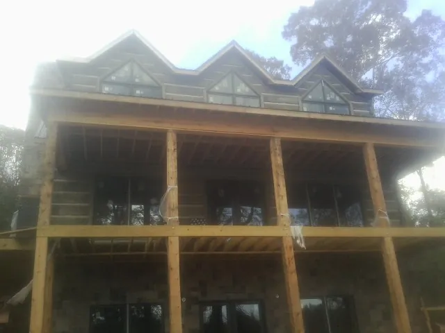 Dormers and porch framing on a large log home under construction — Roof Coating work by our crew in Center Line