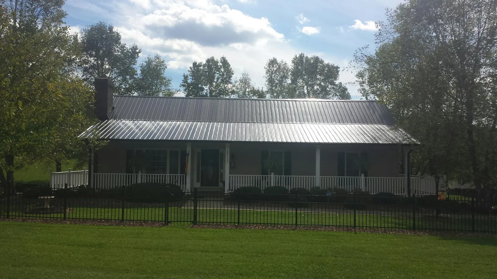 Gray metal roof on a brick ranch with a full width front porch — Gutter Guard Installation work by our crew in Center Line