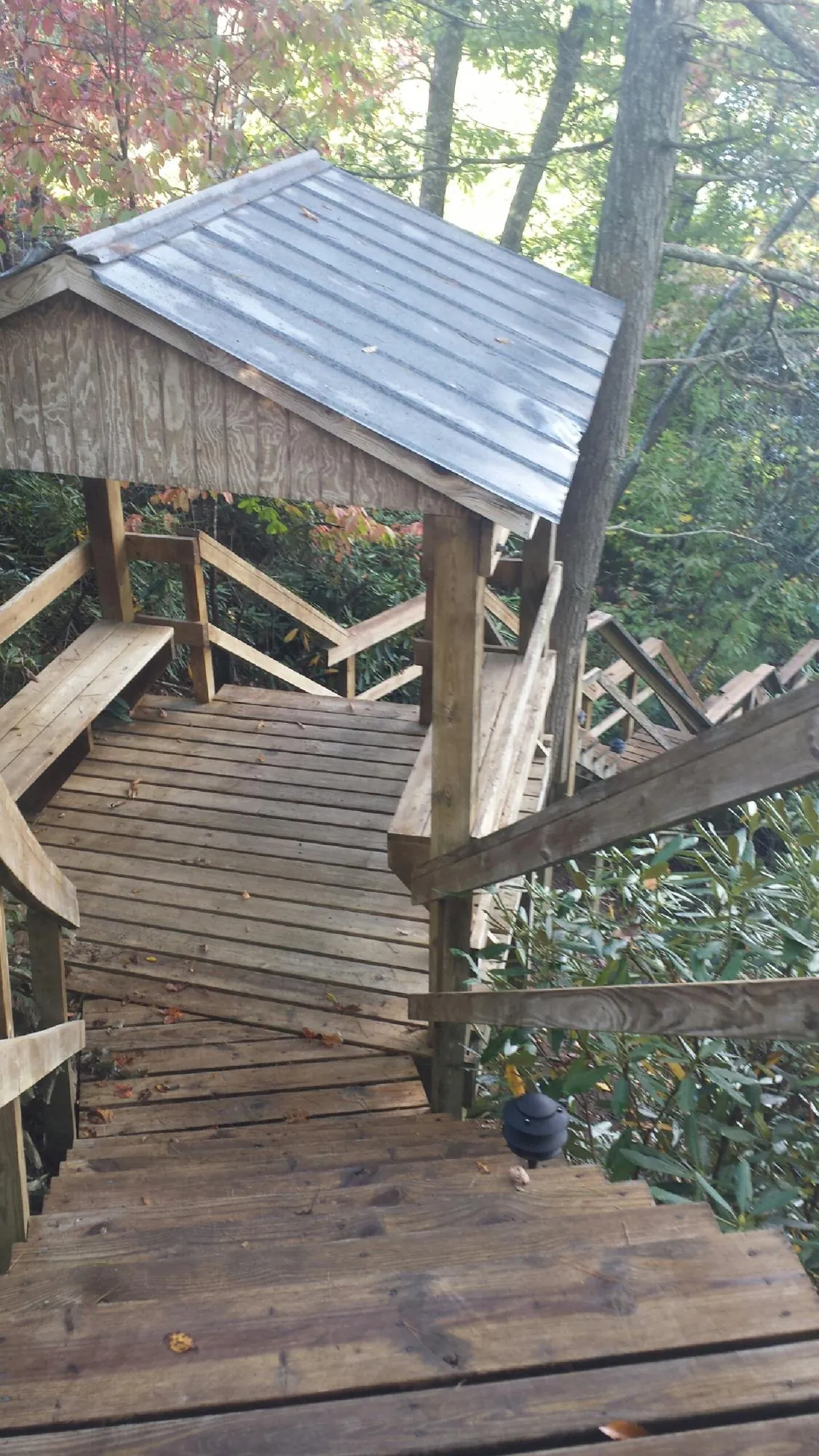 Metal roofed shelter over wooden steps on a wooded walkway — Skylight Repair & Installation work by our crew in Center Line
