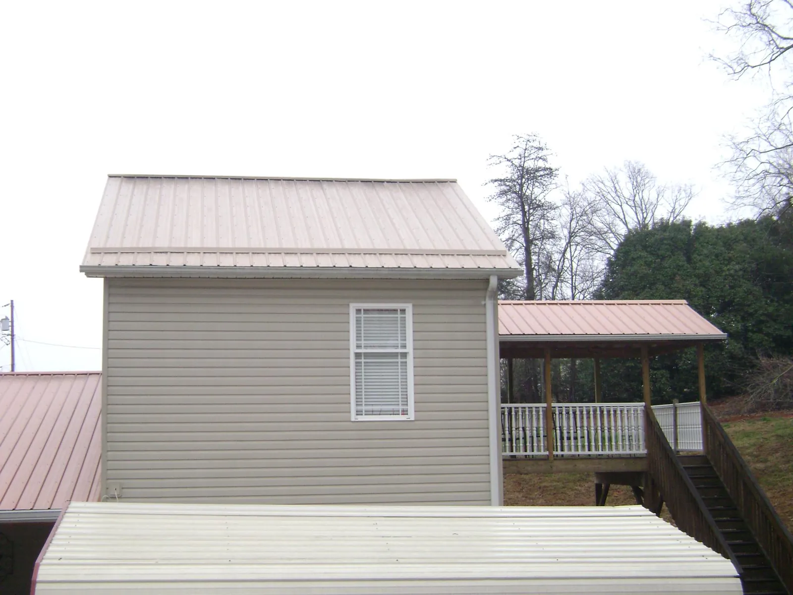 Tan metal roofs on a two story addition and attached porch, from a Roof Replacement job in Center Line